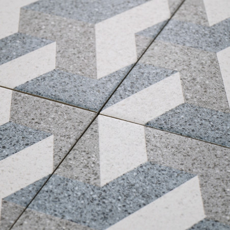 Graue und weiße Fliesen bilden ein Zickzackmuster, das sich an den Fugenlinien kreuzt und so ein geometrisches Muster auf einer 