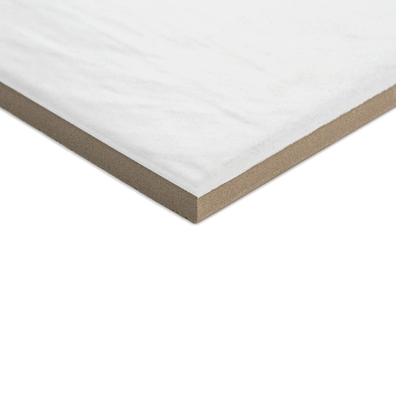 Un azulejo blanco cuadrado con una superficie lisa y bordes beige, que descansa ligeramente inclinado sobre un fondo liso y neut