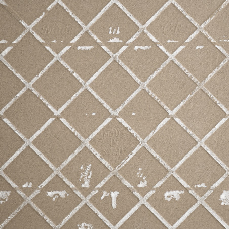 Eine beige Keramikfliese zeigt ein Gitter aus erhabenen, weißen, sich kreuzenden Linien, die Rautenformen bilden. Der Text laute