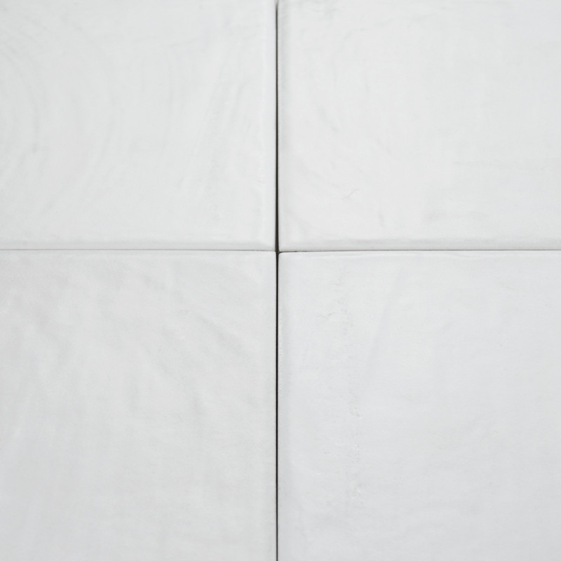 Quatre carreaux carrés gris clair, alignés selon une grille, affichent des textures et des rainures subtiles, créant une surface