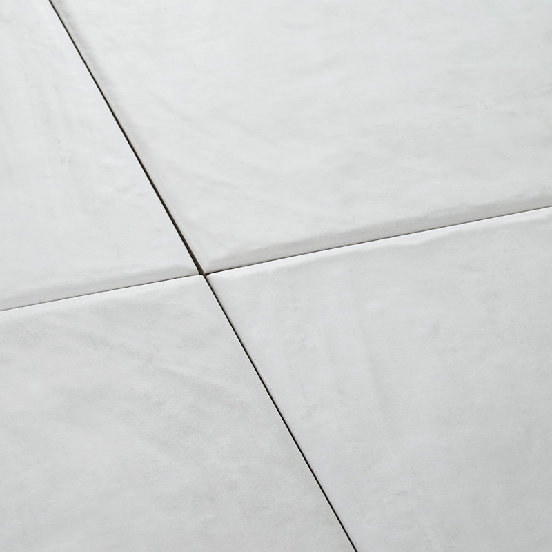 Four white ceramic tiles form a seamless square pattern, creating a smooth, clean surface in a minimalistic and modern setting.