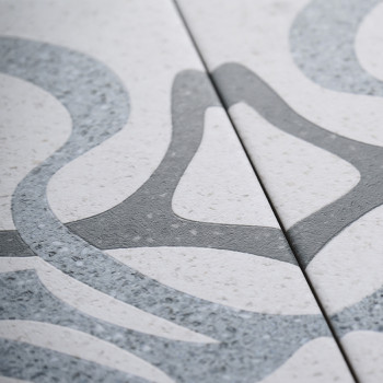 Two ceramic tiles with interlocking gray, smooth abstract patterns displayed against a light speckled background. The patterns f