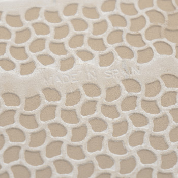 Carreau texturé avec motif en nid d'abeille en relief, affichant le texte « MADE IN SPAIN ». La surface a un fond beige.