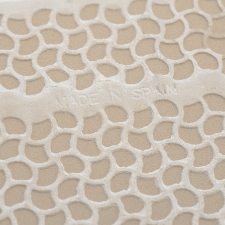 Textured tile with embossed honeycomb pattern, displaying the text `MADE IN SPAIN.` The surface has a beige background.