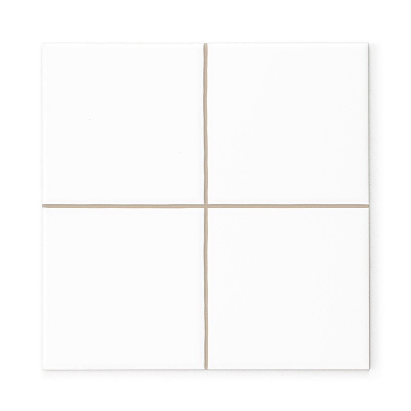 Un carreau de céramique blanche divisé en quatre carrés égaux par de fines lignes de coulis beige, créant un design simple et mi
