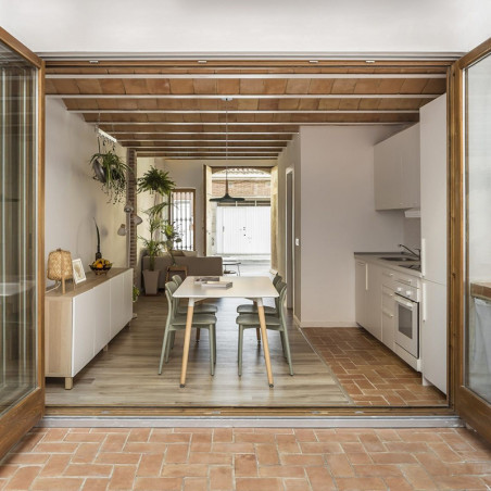 Terrakottafliesen bilden einen Weg, der in einen modernen Küchen-Essbereich führt, umgeben von Holzmöbeln und weißen Möbeln. Terrakottafliesen bilden einen Weg, der in einen modernen Küchen-Essbereich führt, umgeben von Holzmöbeln und weißen Möbeln.