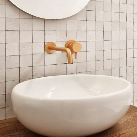 O chuveiro se projeta da parede, cercado por azulejos de terracota brancos, quadrados e brilhantes em um banheiro moderno e mini