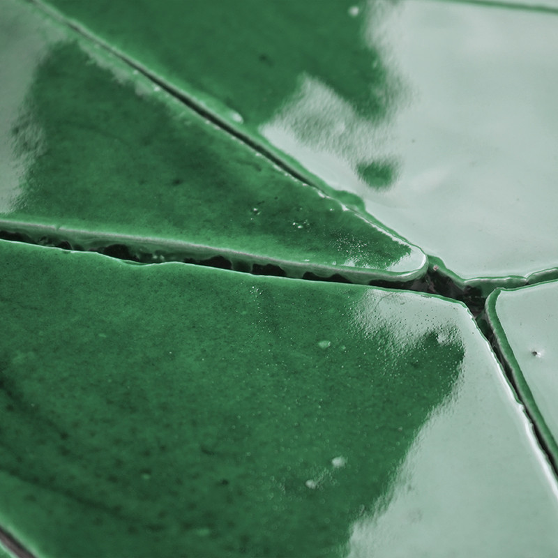 Groene terracottategels, glanzend en reflecterend, passen nauw bij elkaar en creëren een naadloos, geometrisch patroon binnen ee