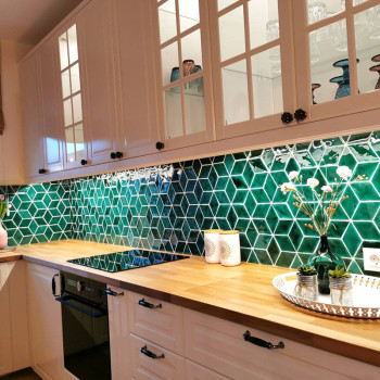 Grüne sechseckige Fliesen bilden eine geometrische Rückwand und ergänzen die Holzarbeitsplatten in einer hellen, modernen Küche 