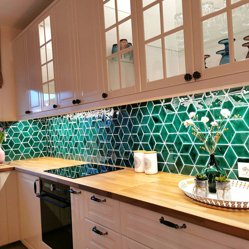 Los azulejos hexagonales verdes forman un protector contra salpicaduras geométrico que complementa las encimeras de madera en un