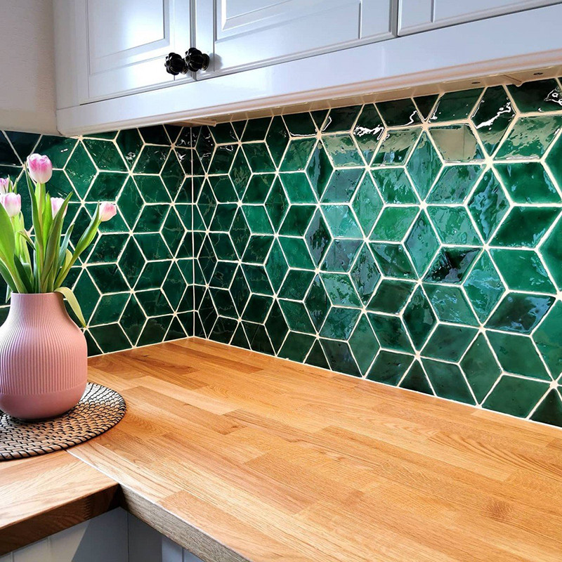 Grüne sechseckige Fliesen bilden einen Backsplash. Eine rosa Vase mit Tulpen steht auf einer Holzarbeitsplatte in einer Küche.
