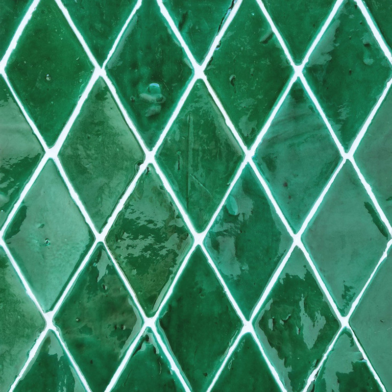 Carreaux de terre cuite verts en forme de losange disposés selon un motif répétitif, vernis réfléchissant captant la lumière, cr