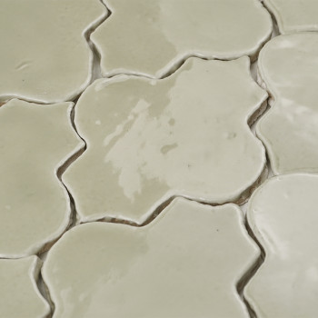 Cream-colored terracotta tiles form a floral pattern, with glossy surfaces reflecting light in an overlapping arrangement.