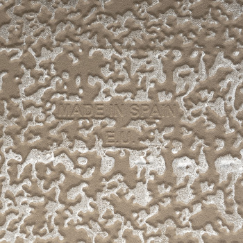 Un carreau beige texturé affiche un motif en relief aux formes aléatoires. Le texte central indique « MADE IN SPAIN EU ». Le car