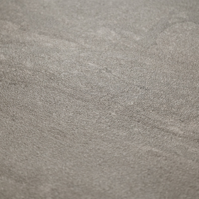 A textured stone tile displays subtle gray color variations and fine, natural patterns, creating an earthy, neutral surface suit