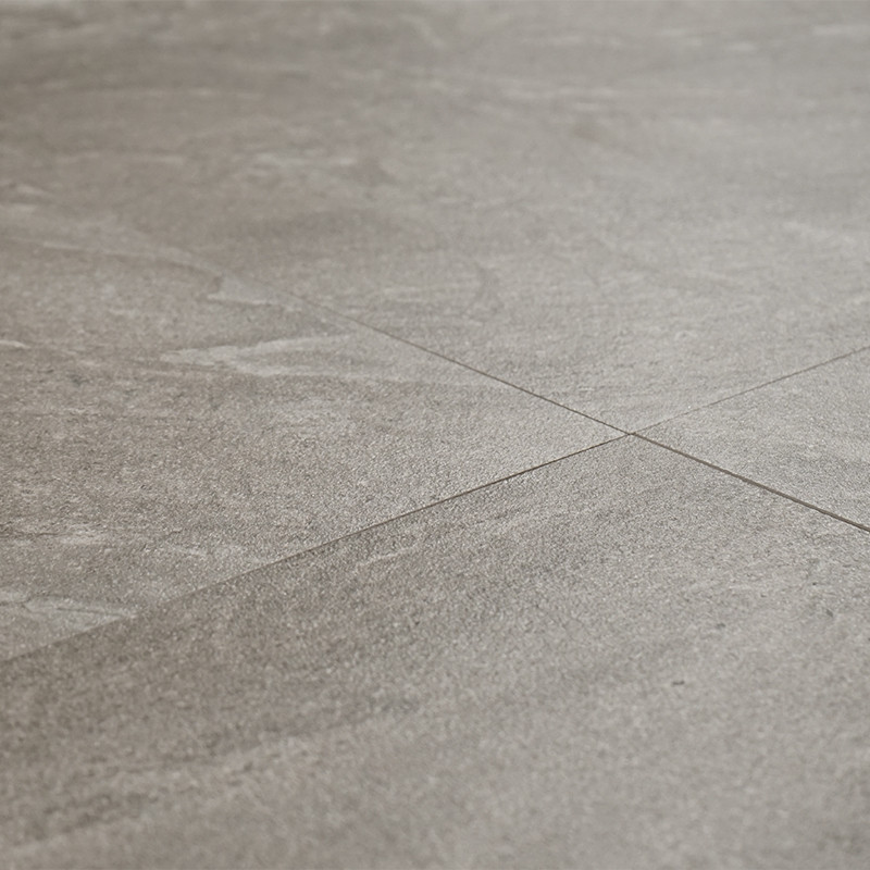 Gray ceramic tiles sit arranged in a neat grid pattern, exhibiting a textured, stone-like finish. The surface appears matte unde