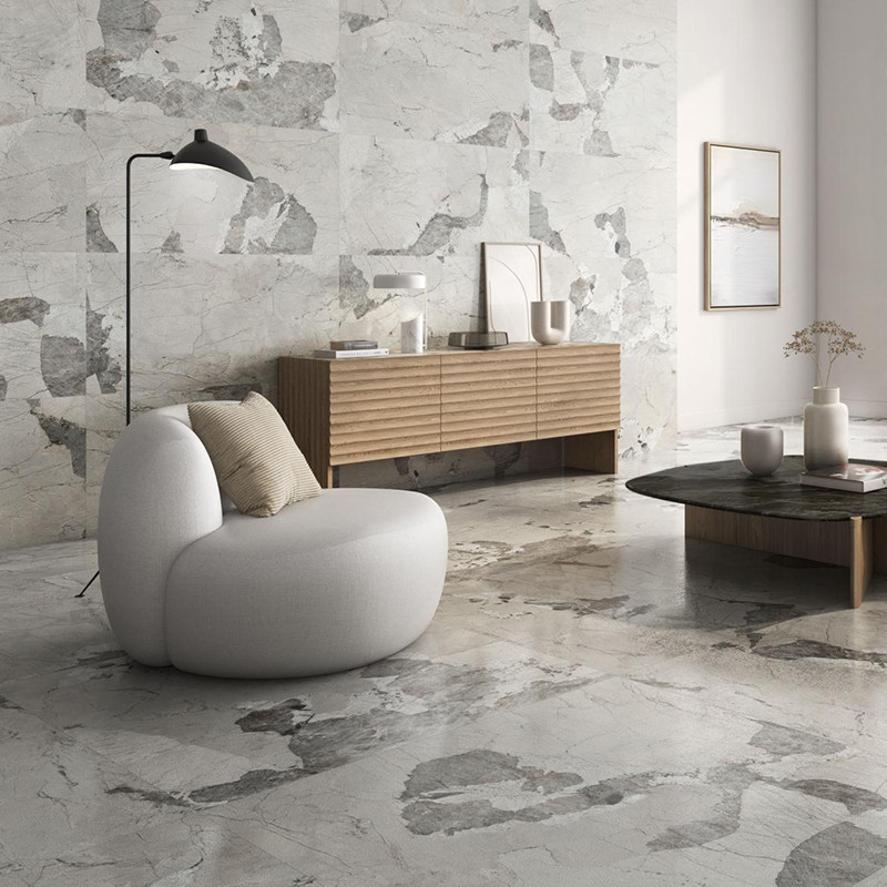 Une chaise grise arrondie repose sur un sol en marbre dans un salon moderne. A proximité, un buffet en bois contient des objets 