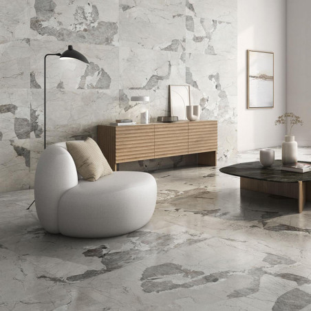 Una silla gris redondeada se asienta sobre un suelo de mármol en una sala de estar moderna. Cerca, un aparador de madera contien Una silla gris redondeada se asienta sobre un suelo de mármol en una sala de estar moderna. Cerca, un aparador de madera contien