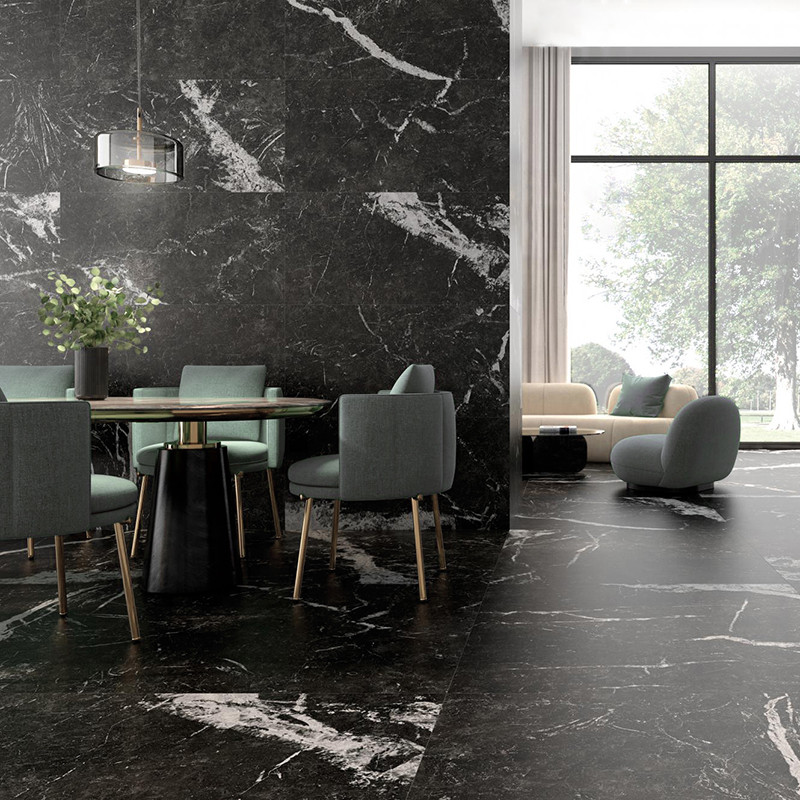A dining area with a glass table and green chairs sits on a black marble floor. Nearby, a cozy seating area with large windows o