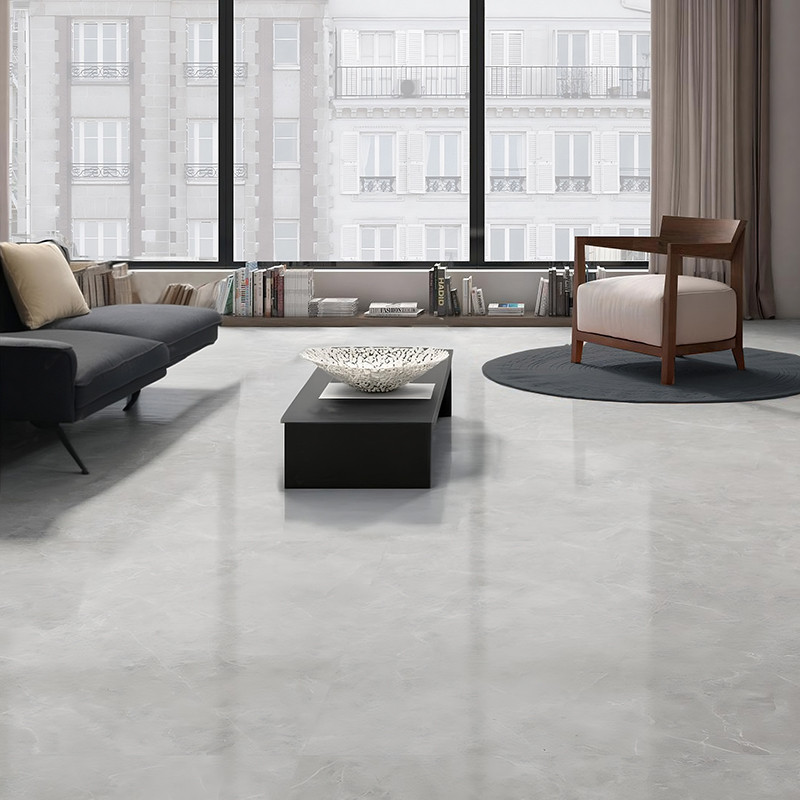 Elegant gray tiles cover the floor, reflecting light from large windows in a modern living room with a sofa, chair, and table.