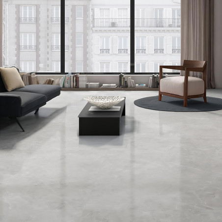 Des carreaux gris élégants recouvrent le sol, reflétant la lumière des grandes fenêtres d'un salon moderne doté d'un canapé, d'u