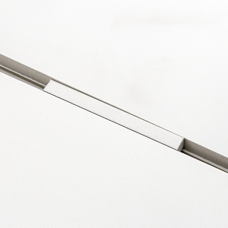 Un carreau blanc avec une rainure rectangulaire étroite et encastrée qui le divise en diagonale, créant une apparence épurée et 