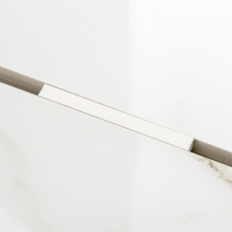 Een rechthoekige, lichtgekleurde tegel rust diagonaal tegen een effen witte achtergrond en vertoont subtiele grijze nerven en ee