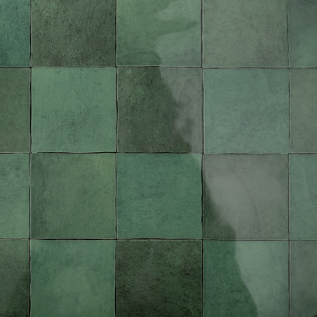 Grüne quadratische Fliesen, die in einem Raster angeordnet sind, reflektieren das Licht und erzeugen eine glänzende Oberfläche.  Grüne quadratische Fliesen, die in einem Raster angeordnet sind, reflektieren das Licht und erzeugen eine glänzende Oberfläche.