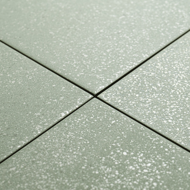 Cuatro azulejos cuadrados de color verde con patrones moteados de blanco se cruzan en el centro, formando una cruz. se colocan s