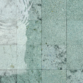 A água cristalina ondula suavemente sobre os ladrilhos de pedra, posicionados na borda de uma piscina infinita, fundindo-se perf