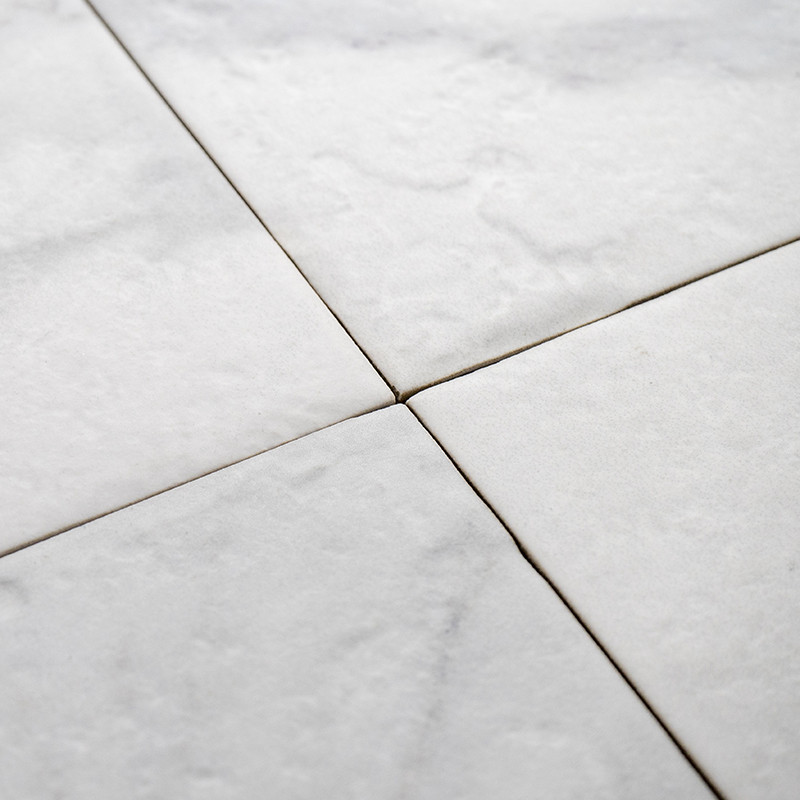 Ladrilhos de mármore branco formam um padrão uniforme, cruzando-se perfeitamente em linhas diagonais. a textura é lisa, criando 