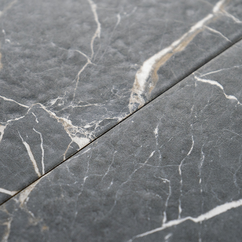 Gray marble tiles display intricate white veins, aligned closely in a seamless junction, creating a sophisticated, natural stone