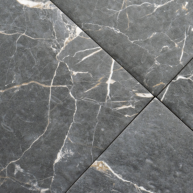 Four grey tiles intersect, featuring white and light brown marble-like veins. They create a textured, natural stone appearance.