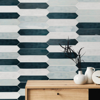 Zeshoekige tegels creëren een afwisselend donker en licht patroon op een muur. In een houten kast staan ​​drie witte vazen ​​met