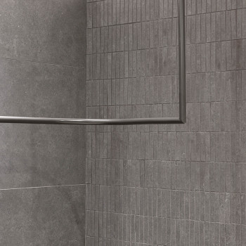 Grijze rechthoekige tegels, uitgelijnd in een rasterpatroon, vormen een hoekwand. Geen zichtbare voeglijnen, waardoor een strakk