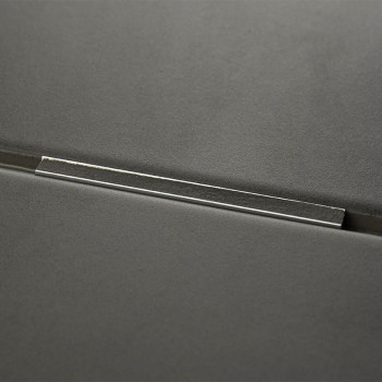 Um ladrilho cinza escuro com uma barra metálica inserida em sua superfície, refletindo a luz, contra um fundo suave e minimalist