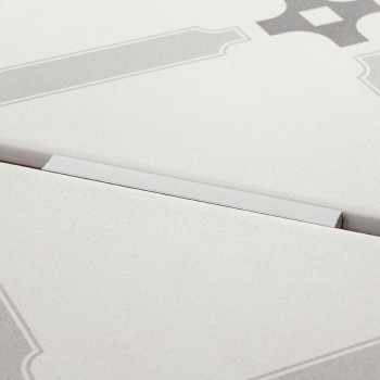 Eine helle Fliese mit geometrischen Mustern ist teilweise erhöht und bildet einen subtilen Winkel vor einem schlichten Hintergru