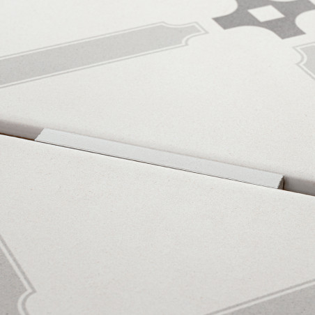 Eine helle Fliese mit geometrischen Mustern ist teilweise erhöht und bildet einen subtilen Winkel vor einem schlichten Hintergru