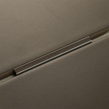 Ein Metallbesatz liegt zwischen zwei mattgrauen Fliesen und bildet eine präzise Naht in einem modernen, minimalistischen Design.