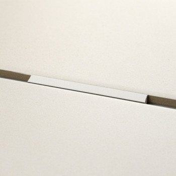 Eine rechteckige weiße Fliese liegt horizontal auf einer grauen Oberfläche mit einer dünnen Nut darunter und schafft so eine min