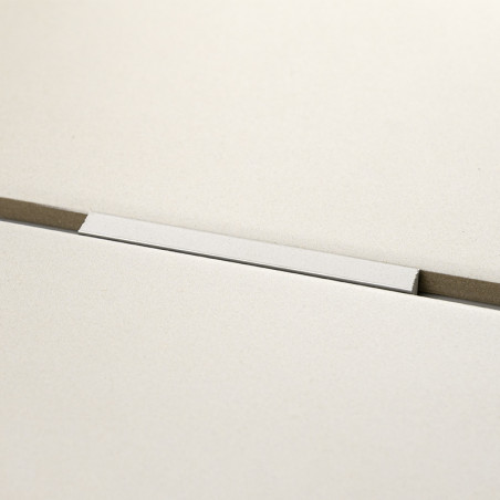 Eine rechteckige weiße Fliese liegt horizontal auf einer grauen Oberfläche mit einer dünnen Nut darunter und schafft so eine min