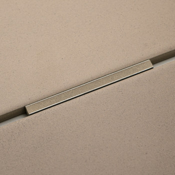 Ladrilhos retangulares bege se alinham com uma fina faixa metálica que os separa, criando uma aparência moderna e perfeita em um