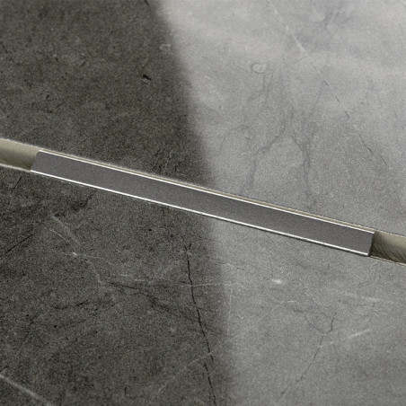 Eine rechteckige graue Fliese, diagonal halbiert, zeigt eine Naht mit unterschiedlichen Grautönen. Die Oberfläche weist eine dez