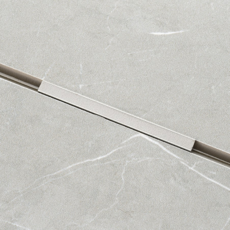 A rectangular, light grey tile features a subtle marble pattern with faint white veins. A thin, horizontal metallic strip inters