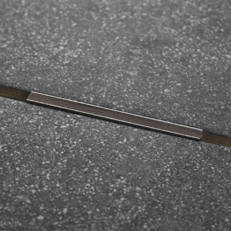 Eine dunkelgraue, gesprenkelte Fliese verfügt über einen dünnen Metallstreifen, der diagonal über die Mitte verläuft und ein mod