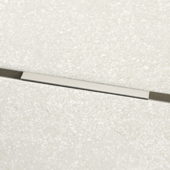 Rechthoekige, metalen strook ingebed in beige getextureerde tegels, ligt horizontaal. De strook zorgt voor een subtiele verdelin