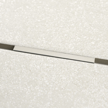 Rechteckiger Metallstreifen, eingebettet in strukturierte beige Fliesen, liegt horizontal. Der Streifen erzeugt eine subtile Unt