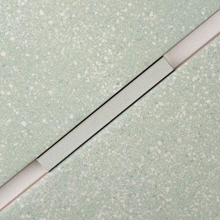 Um ladrilho retangular com um padrão claro salpicado é cruzado diagonalmente por uma faixa fina e elevada, criando um contraste  Um ladrilho retangular com um padrão claro salpicado é cruzado diagonalmente por uma faixa fina e elevada, criando um contraste