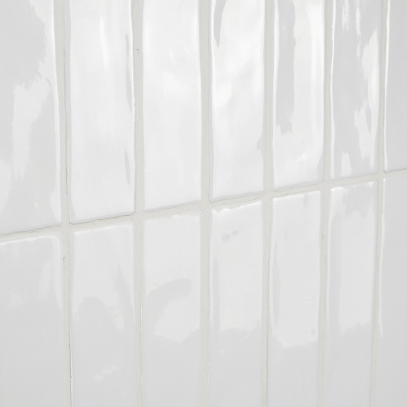 Los azulejos rectangulares de color blanco brillante reflejan la luz, dando una impresión de limpieza y simplicidad en una pared