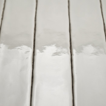Ladrilhos cerâmicos retangulares brilhantes refletem a luz, dispostos verticalmente com linhas estreitas de argamassa escura, cr